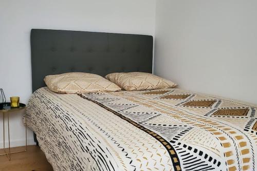 a bed with a black headboard and two pillows on it at Tulsa Home - Superbe appartement de deux chambres - avec terrasse privée in Osny