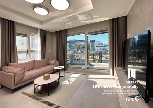 a living room with a couch and a large window at Y COLLECTION by UH FLAT OSIRIA in Busan