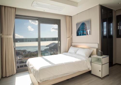 a bedroom with a large bed and a large window at Y Collection by UH FLAT Osiria in Busan