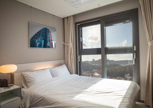 a bedroom with a bed and a large window at Y COLLECTION by UH FLAT OSIRIA in Busan