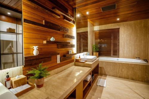 Crystalkuta Hotel - Bali في كوتا: حمام بجدران خشبية وحوض استحمام ومغسلة