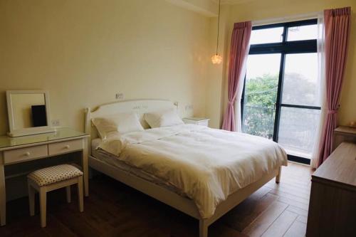 a bedroom with a bed and a desk and a window at Country Road B&B in Guangfu