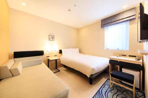 een hotelkamer met een bed en een bank bij Hotel Nihonbashi Saibo in Tokyo