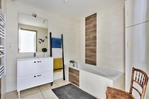 uma casa de banho branca com uma banheira e um lavatório em Maison Saint-Thomas em Cuiseaux