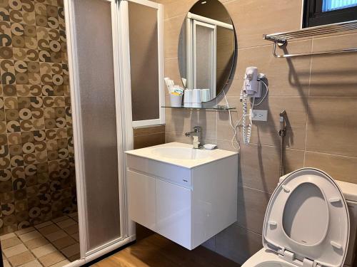 a bathroom with a toilet and a sink and a mirror at Country Road B&B in Guangfu