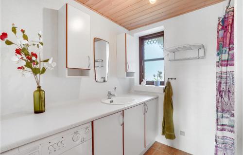 uma casa de banho branca com um lavatório e um vaso de flores em 3 Bedroom Nice Home In Vinderup em Vinderup