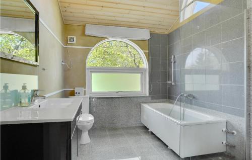 a bathroom with a tub and a sink and a toilet at 4 Bedroom Beautiful Home In Rørvig in Rørvig