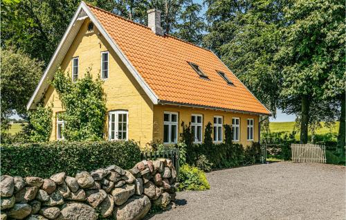 a yellow house with an orange roof and a stone wall at Risegård, Lejl, A in Åkirkeby