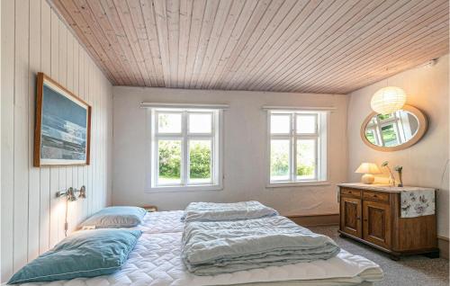 a bedroom with two beds and a mirror and windows at Risegård, Lejl, A in Åkirkeby
