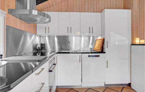 a kitchen with white cabinets and a silver refrigerator at 3 Bedroom Awesome Home In Middelfart in Middelfart