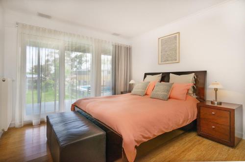 a bedroom with a bed with orange sheets and a window at Mt Martha Retreat in Mount Martha