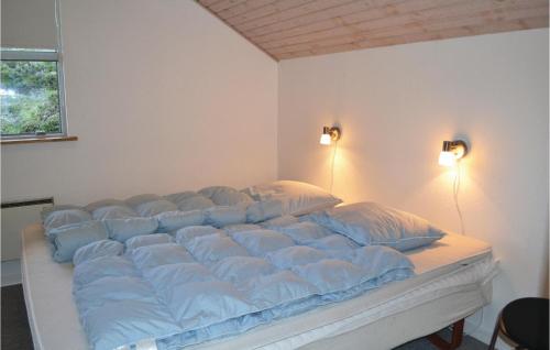 a large bed with blue pillows on it in a room at Pet Friendly Home In Henne With Sauna in Henne Strand