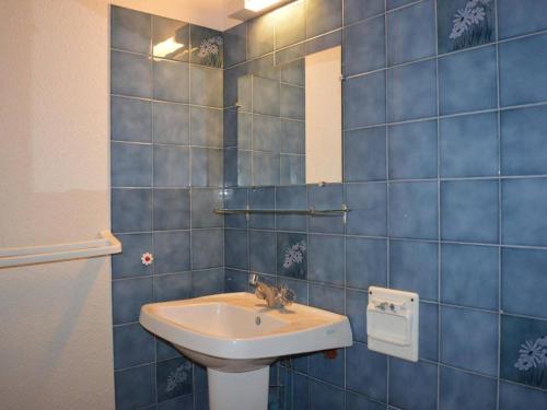 La salle de bains est pourvue d'un lavabo et d'un mur carrelé bleu. dans l'établissement Appartement à 200m de la plage, 2 pièces cabine, 6 couchages, loggia, parking, quartier calme - FR-1-229B-138, à Narbonne