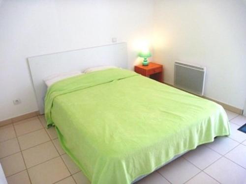 - une chambre avec un lit vert et une lampe sur une table dans l'établissement Appartement tout confort avec piscine et accès direct à la plage - FR-1-387-74, à Marseillan