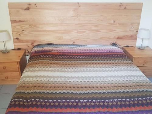 une chambre avec un lit avec une tête de lit en bois dans l'établissement T2 calme avec terrasse et accès à la piscine au bord du lac - FR-1-195-77, au Barcarès