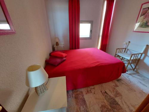 - une chambre avec un lit rouge et une table avec une lampe dans l'établissement Appartement 2 pièces avec terrasse en front de mer à louer - FR-1-423-181, au Grau-dʼAgde