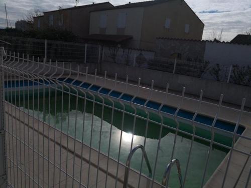 - une piscine derrière une clôture avec de l'eau dans l'établissement Maison avec Piscine Proche Plage, 5 Couchages et Parking Privé - FR-1-326-685, à Marseillan