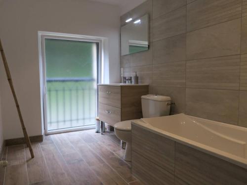 une salle de bain avec une baignoire, des toilettes et un lavabo dans l'établissement Maison rénovée pierre, jardin, WIFI, 400m mer, St Quay-Perros - FR-1-368-258, à Saint-Quay-Perros