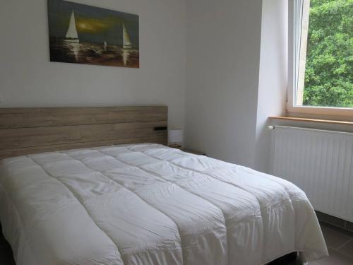 - un lit blanc dans une chambre avec fenêtre dans l'établissement Maison rénovée pierre, jardin, WIFI, 400m mer, St Quay-Perros - FR-1-368-258, à Saint-Quay-Perros