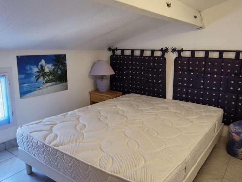 une chambre avec un lit avec un couvre-lit blanc dans l'établissement Maison 3 pièces, 5 couchages avec terrasse et piscine, parking privé, à Marseillan - FR-1-326-705, à Marseillan