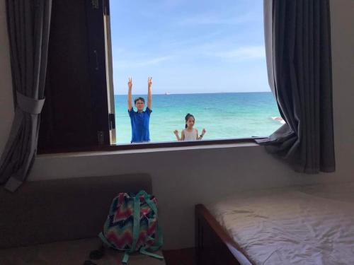 a man and a woman looking out a window at the ocean at Mũi Dinh Hotel in Phan Rang