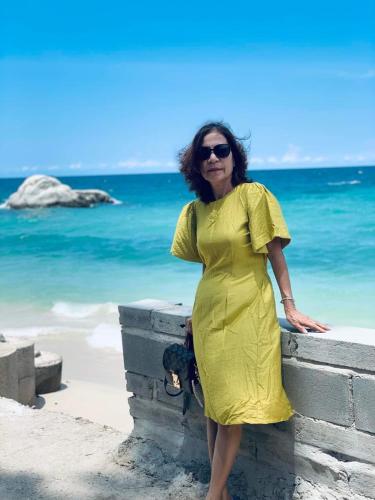 a woman in a yellow dress standing next to the ocean at Mũi Dinh Hotel in Phan Rang