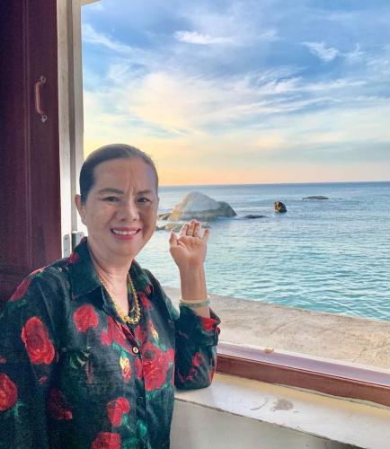a woman standing next to a window looking at the ocean at Mũi Dinh Hotel in Phan Rang