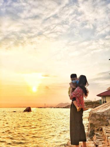 a woman holding a child standing on the shore of a body of water at Mũi Dinh Hotel in Phan Rang