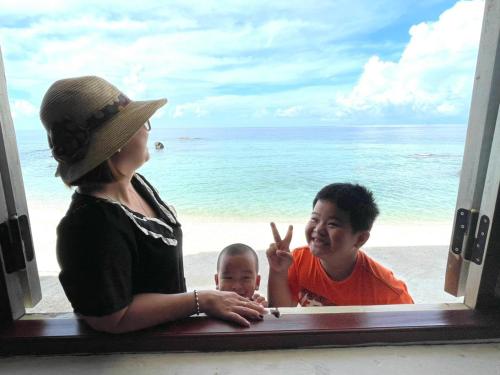 a woman and a child looking out a window at the beach at Mũi Dinh Hotel in Phan Rang