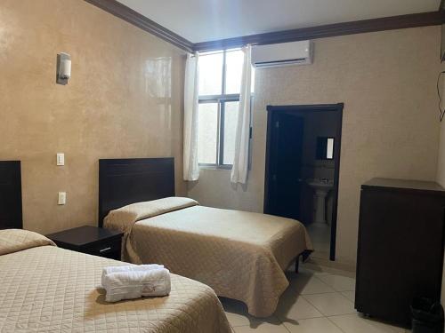 a hotel room with two beds and a window at Hotel San Salvador in San Juan de los Lagos