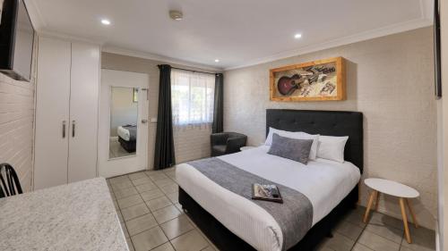 1 dormitorio con 1 cama grande y baño en Country Leisure Motor Inn, en Dubbo