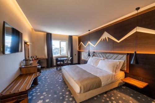 a hotel room with a large bed and a bench at Grand Kartal Hotel in Kartalkaya
