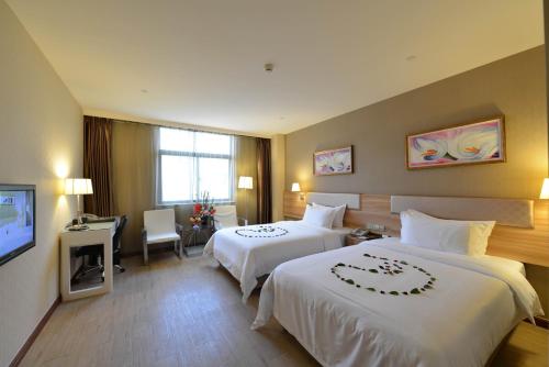 a hotel room with two beds and a television at Dayi Yihao hotel in Xiamen