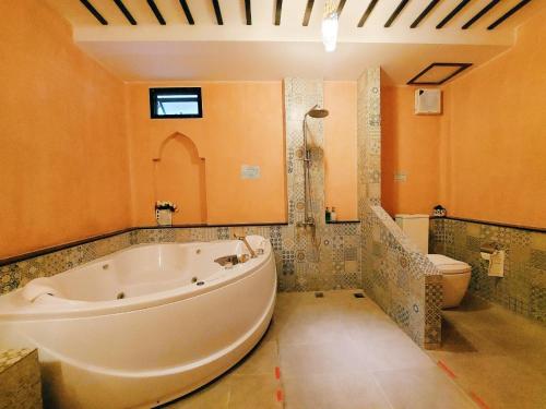 a bathroom with a large tub and a toilet at Retro Box Hotel Chumphon in Chumphon
