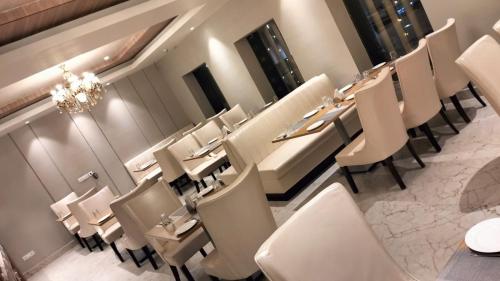 a restaurant with white chairs and tables and a chandelier at PIPUL PADMAJA PRIDE in Cuttack