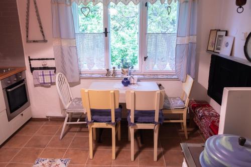a dining room with a table and chairs and windows at Chaloupka pod skalou in Libošovice