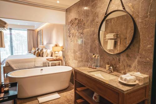 ein Bad mit einer Badewanne, einem Bett und einem Spiegel in der Unterkunft Goya Boutique Resort in Ubud