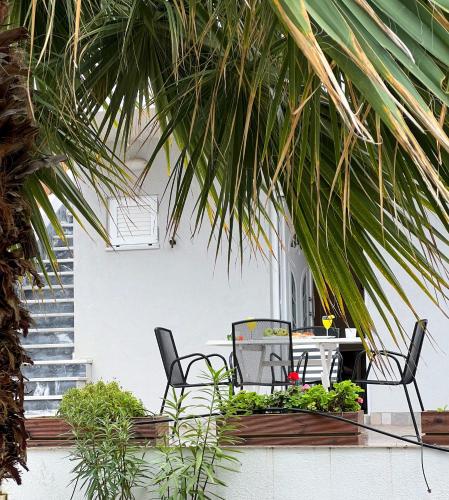 a patio with a table and chairs and palm trees at Galini Studios Paralia Platanou in Akrata