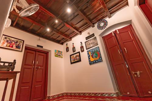 two red doors in a room with paintings on the walls at Anamala Serenity Homestay Kerala in Lakkidi