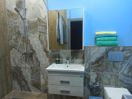 een badkamer met een wastafel en een douche met een spiegel bij 1-ком.квартира от ИП Дома света, перекресток Кенесары-Кумисбекова in Astana