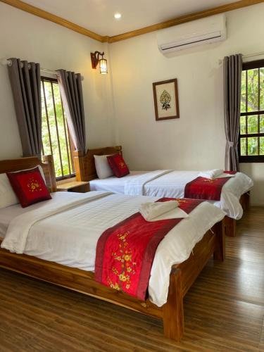 a bedroom with two beds and two windows at Liberty Place in Luang Prabang