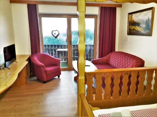 a living room with a red chair and a balcony at Romantik Appartements in Sankt Englmar