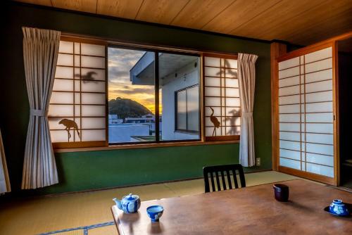 une salle à manger avec une table et une grande fenêtre dans l'établissement Sawaki, à Imabari