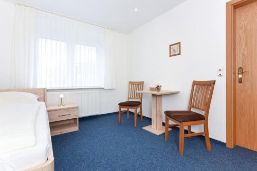 a bedroom with a bed and two chairs and a table at Hotel-Pension Marlies in Neuharlingersiel