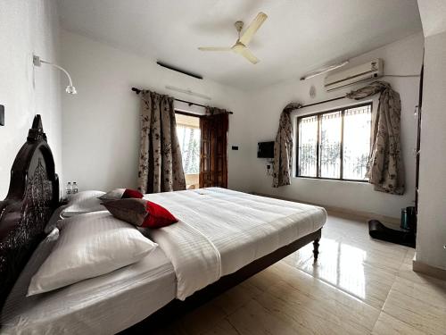 a bedroom with a large bed with a ceiling fan at Kovalam Beach House in Trivandrum