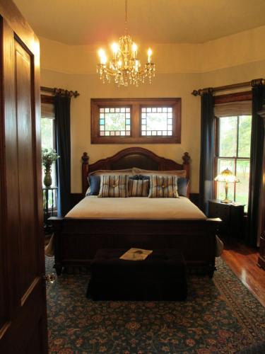 a bedroom with a large bed and a chandelier at Adair Manor Bed & Breakfast in Adairsville