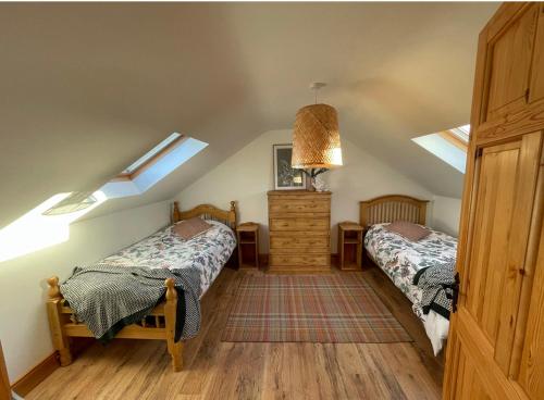 a attic bedroom with two beds and skylights at Modern self catering apartment, Miltown Malbay in Milltown Malbay