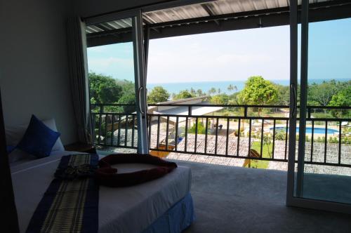 a bedroom with a bed and a balcony with a view at Chom Dao Resort in Ko Lanta