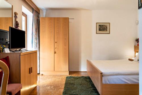 1 dormitorio con 1 cama, armario y TV en Figisterhof, en Chiusa