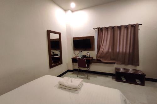 1 dormitorio con cama, espejo y TV en OYO 92089 Hotel Subur, 